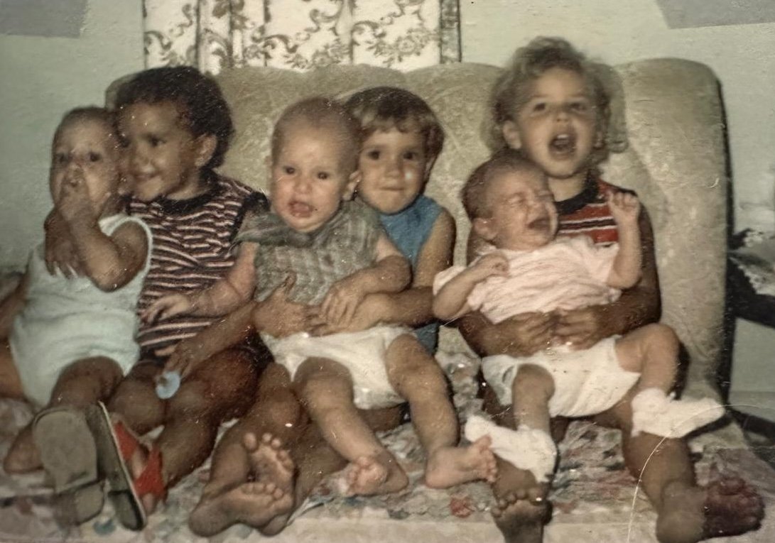 A group of cousins as babies, together on a sofa