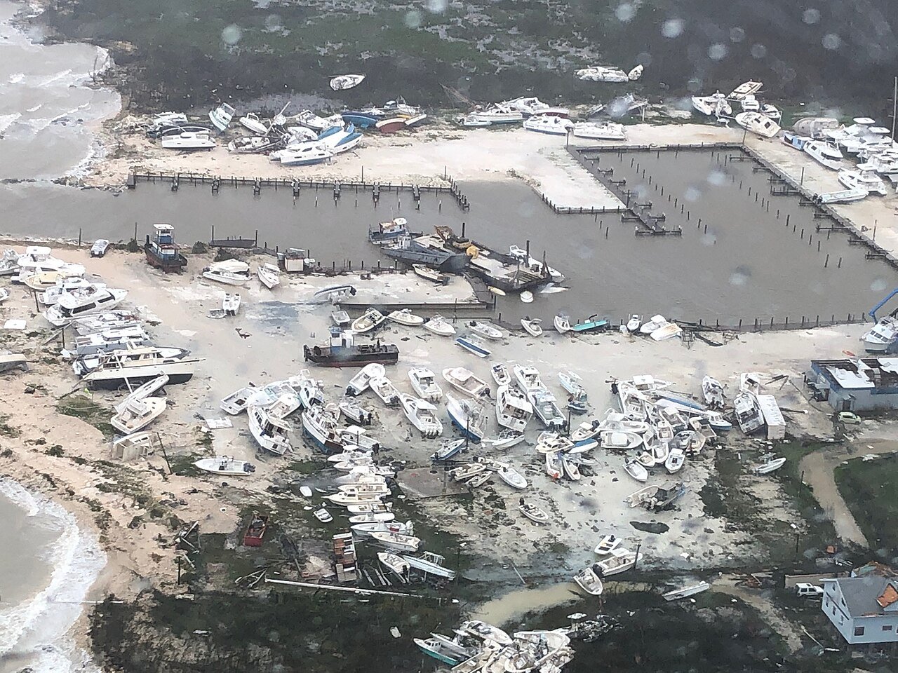 Aerial view of a marina after Hurricane Dorian, with dozens of boats wrecked and scattered along the shore and docks
