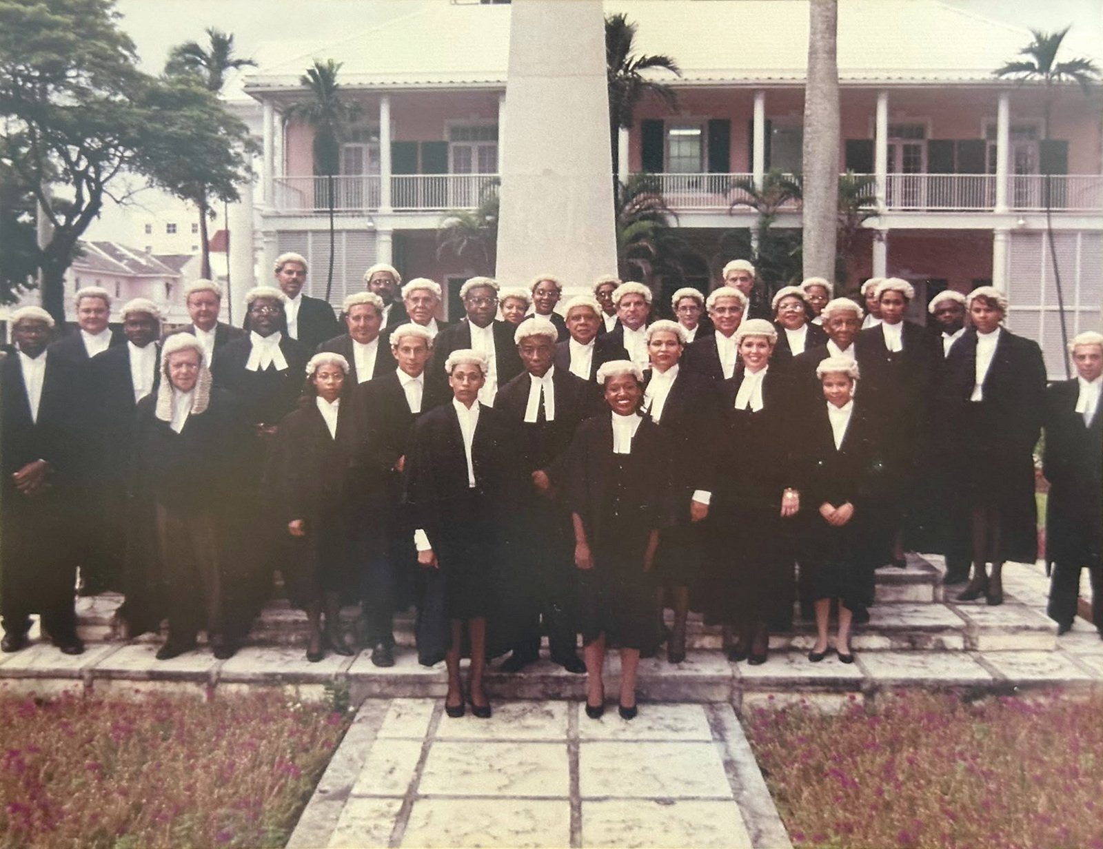 A group of barristers in wigs and robes gathered on the steps of a government building