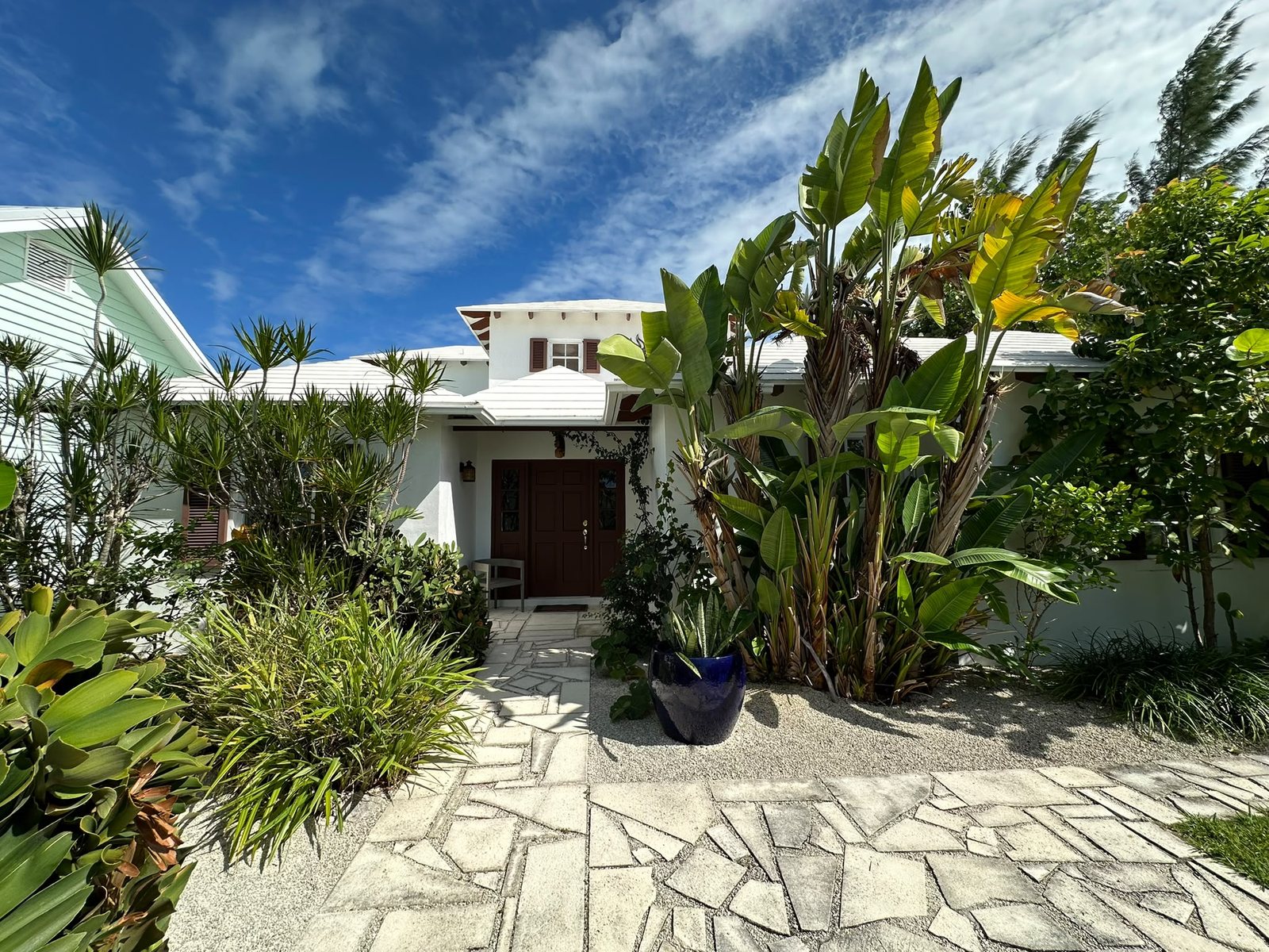 The entrance to Orange House, Abaco, a white Bahamian home framed by tropical greenery including tall bird-of-paradise plants