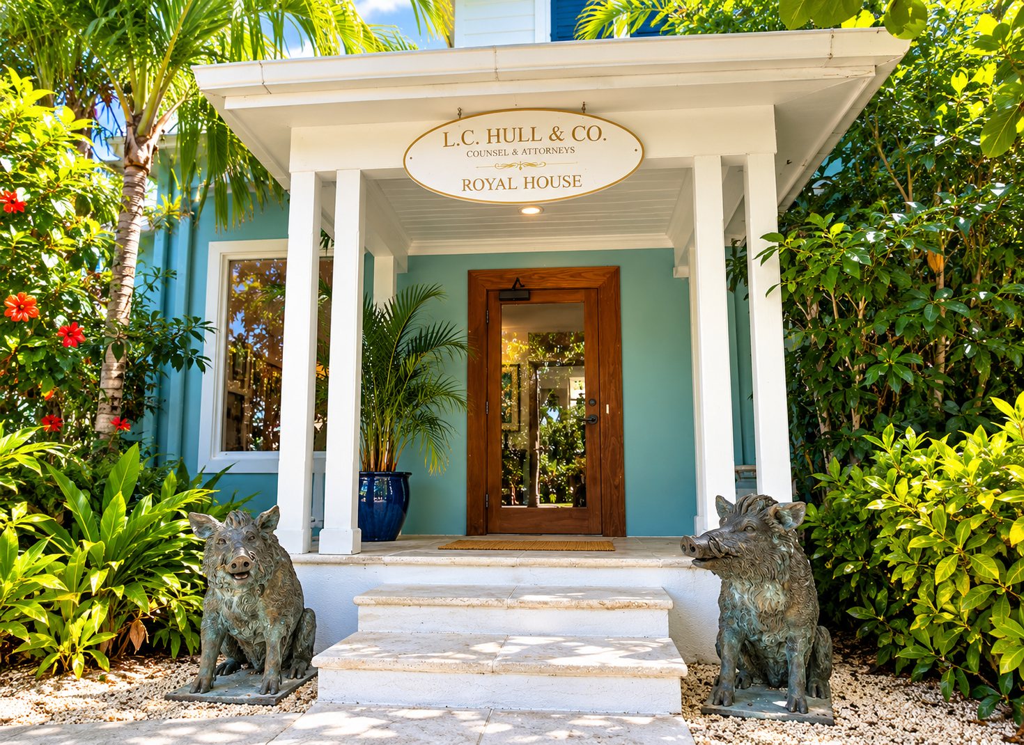 The rear entrance of Royal House, with an L.C. Hull and Co. sign above a teal door flanked by two bronze boar statues